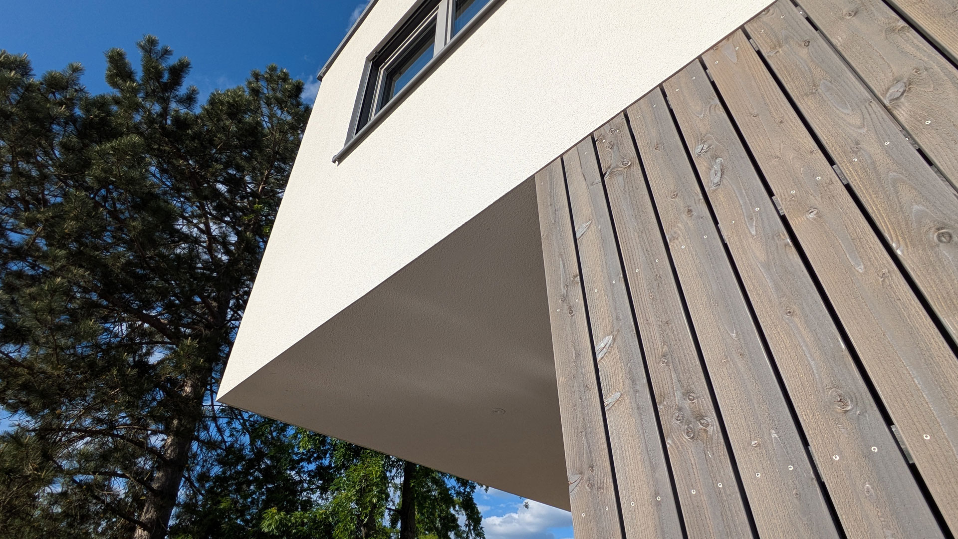 Detailansicht eines auskragenden Gebäudeteils mit Holzverkleidung
